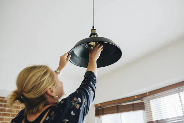 Woman changing a light bulb in her home