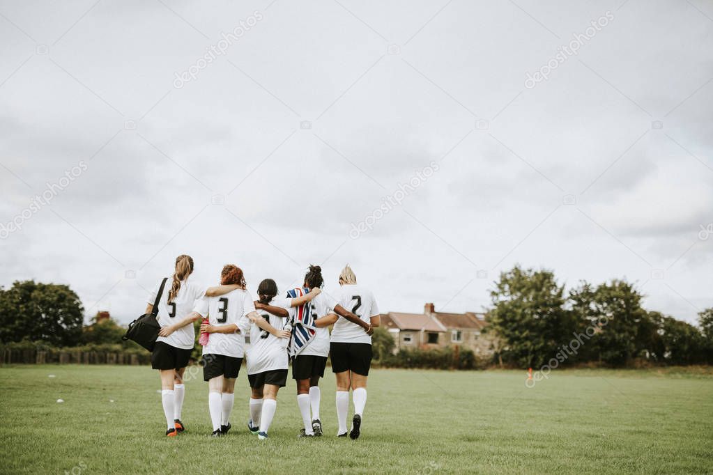 Female football players huddling and walking together