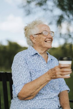 Parkta bir paket servisi olan restoran kahve sahip mutlu kadın kıdemli