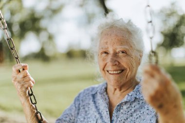 Kadın kıdemli neşeli bir Bahçesi, bir salıncak üzerinde