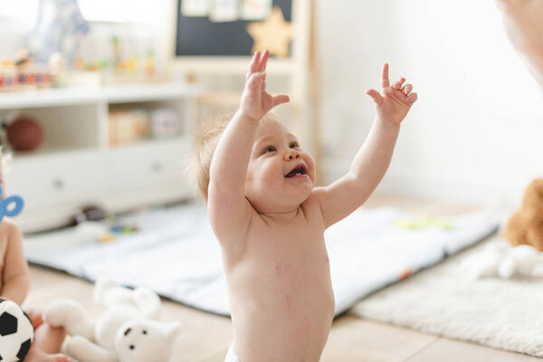Cheerful baby reaching out to his mum