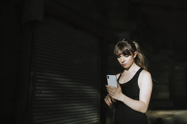 Karanlık Bir Sokakta Mesajlaşma Sportif Kadın — Stok fotoğraf