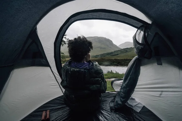 Woman sitting in a tent while it\'s raining