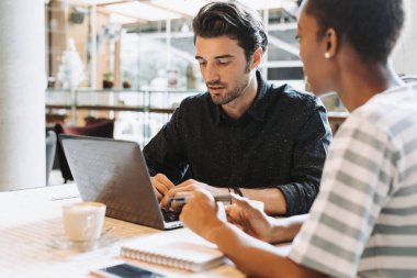 İş arkadaşları bir dizüstü bilgisayarda çalışmalarını tartışıyor