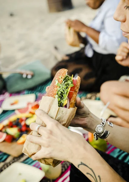 在海滩上吃三明治的妇女 — 图库照片