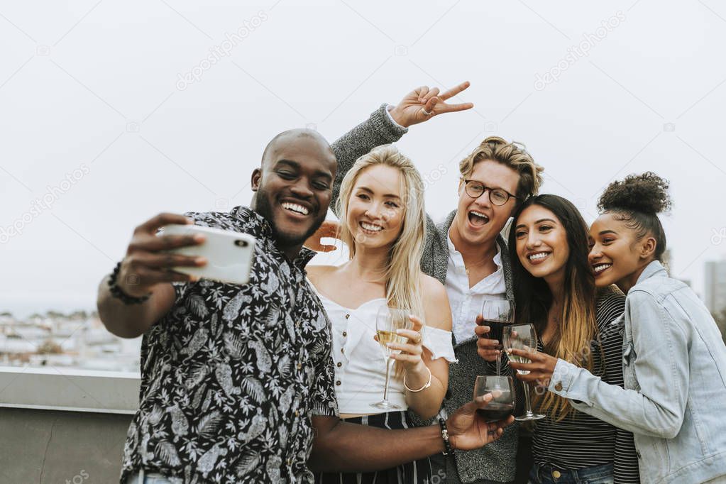 Diverse group of friends taking a selfie at a rooftop party