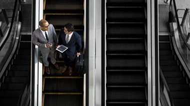 Bir yürüyen merdiven üzerinde tartışan iş adamları