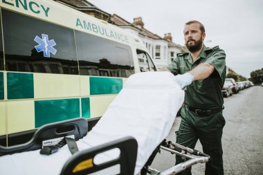 Male paramedic moving the ambulance stretcher clipart