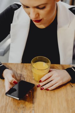 Bir bardak meyve suyu olması ve telefonunu kontrol kadın