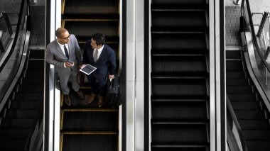 Bir yürüyen merdiven üzerinde tartışan iş adamları