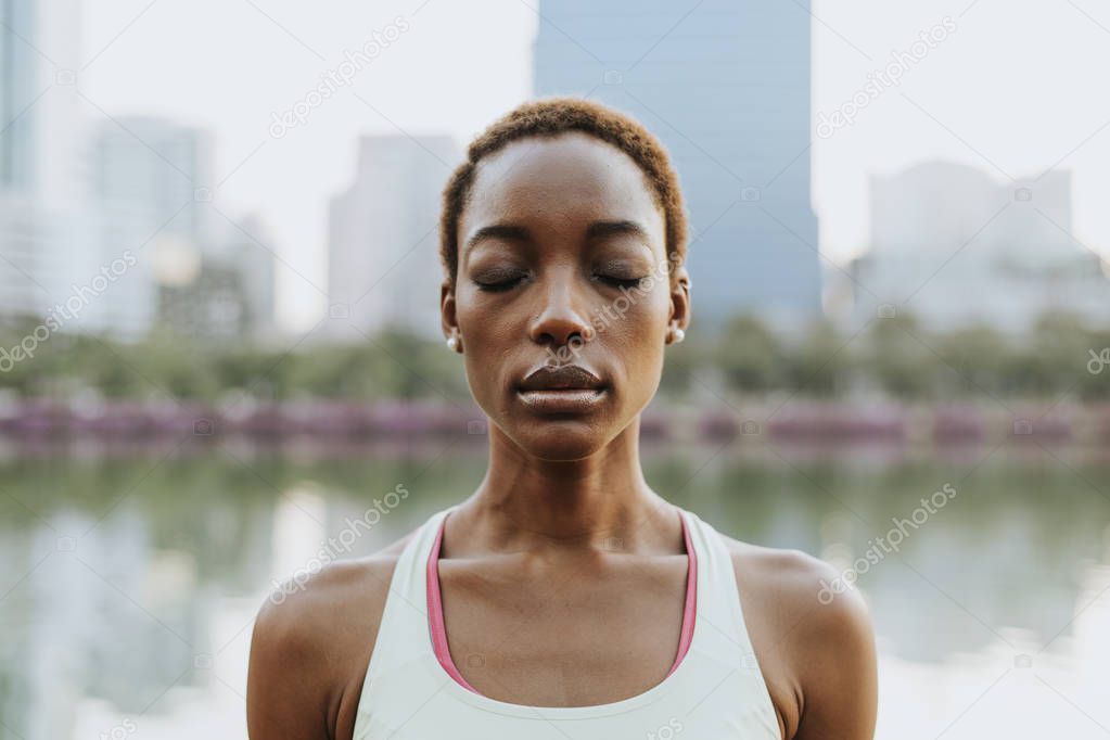 Black lady making a meditation at a park