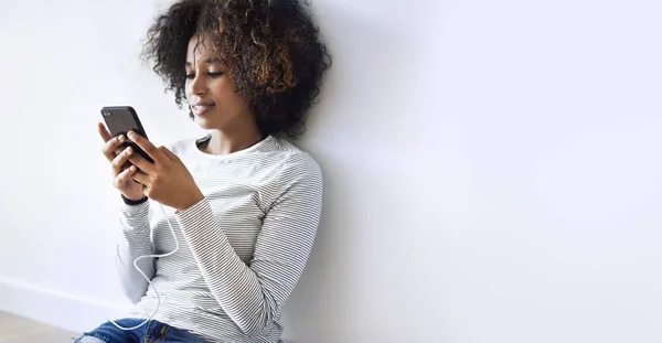 黑人妇女发短信在地板上 而充电她的手机 — 图库照片