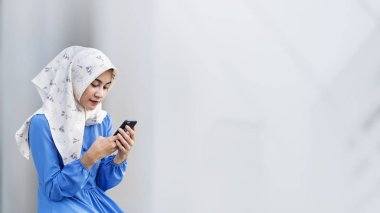 Parkta bir akıllı telefon kullanan Müslüman kız