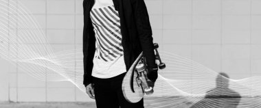 Gri tonlamalı bir kaykay tutan genç adam