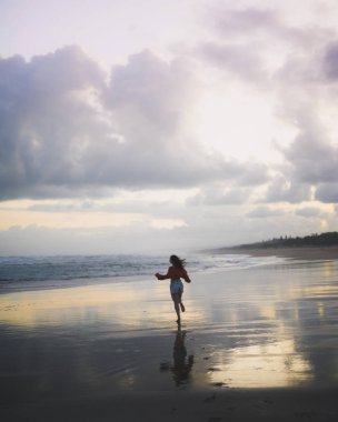 Sahilde koşan kadının arka görünümü