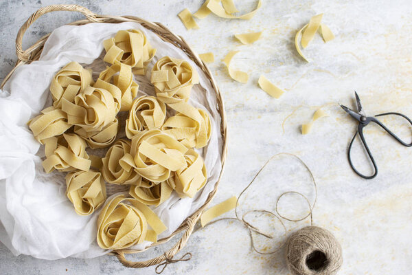 Uncooked pappardelle pasta on a wooden basket