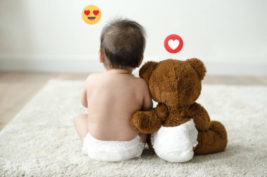 Oyuncak ayının yanında oturan bebek