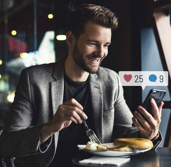 Happy man using social media on his smartphone in a cafe