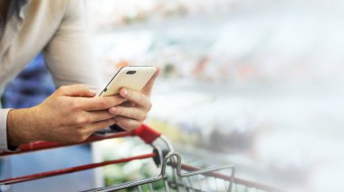 Süpermarkette telefonunu kullanan adam