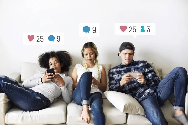 Kanepede Oturan Genç Yetişkinler Akıllı Telefonlarında Sosyal Medya Kullanıyorlar — Stok fotoğraf