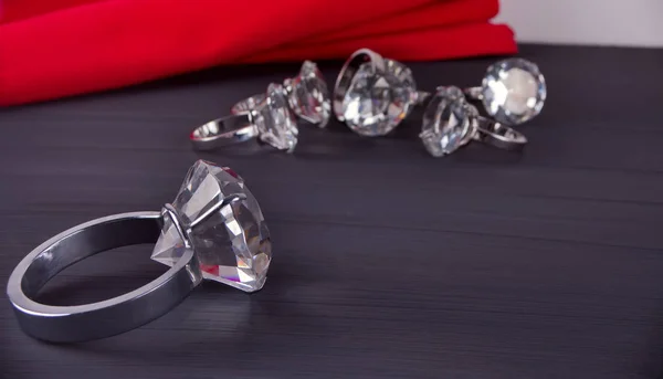 Giant big diamond ring on the table. In the background a bunch of rings and red table napkin