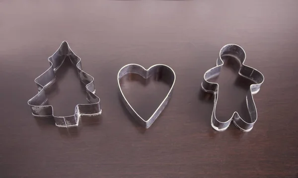 Christmas cookie cutters tree, heart, gingerbread man, star on the wooden table