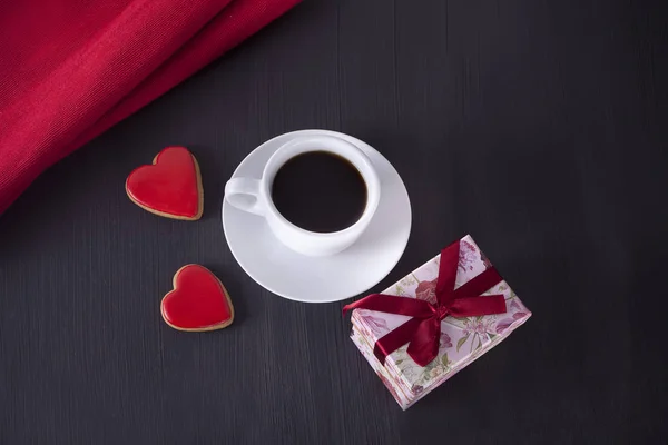 Cup of coffee and a heart shaped cookies on the wooden table