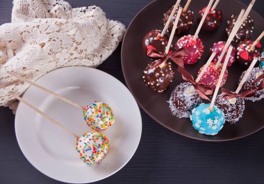 Ahşap bir masa üzerinde beyaz ve koyu çikolata ile dekore edilmiş çeşitli kek çıkar