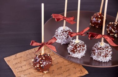 Ahşap bir masa üzerinde koyu çikolata ile dekore edilmiş çeşitli kek çıkar