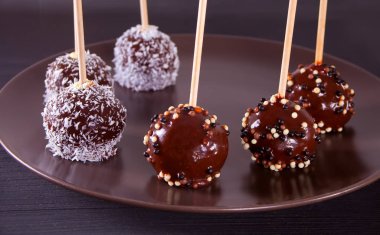 Ahşap bir masa üzerinde koyu çikolata ile dekore edilmiş çeşitli kek çıkar