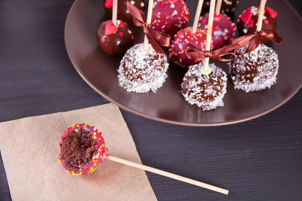 Ahşap bir masa üzerinde beyaz ve koyu çikolata ile dekore edilmiş çeşitli kek çıkar