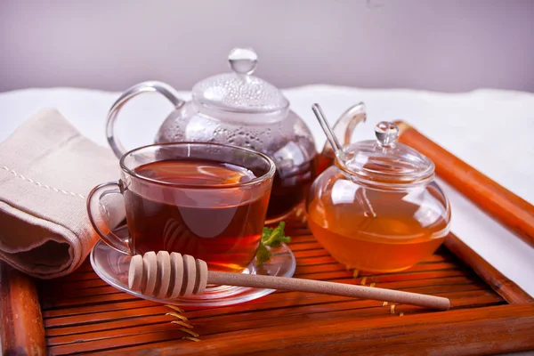 紅茶ポットと木製のトレイの上に蜂蜜入りの熱い紅茶のカップ — ストック写真