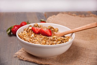 Bir tabak müsli ve ahşap masa üzerinde çilek ile