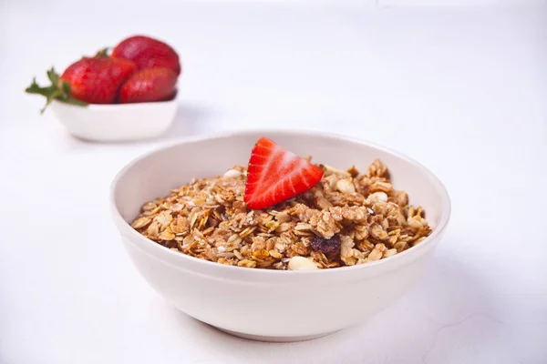 Um prato com muesli e morangos em um fundo branco . — Fotografia de Stock