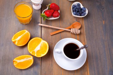 Kahve, portakal, çilek, yumurta, süt ve bal ahşap arka plan üzerinde bir