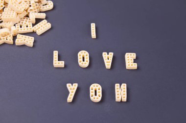 Metin seni harf şeklinde makarna ile siyah ahşap masa arka plan üzerinde yazılı seviyorum