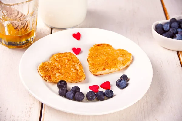 Plate of two pancakes in the shape of heart with berries on white table — Stock Photo, Image