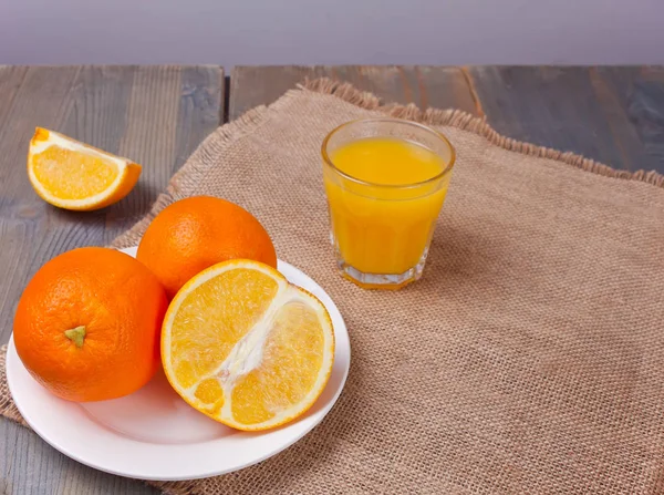 Copo de suco de laranja e fatias de frutas de laranja na mesa de madeira . — Fotografia de Stock