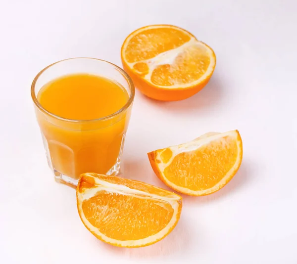 Copo de suco de laranja e fatias de frutas de laranja no fundo branco — Fotografia de Stock