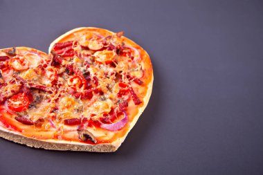 Pizza Sevgililer günü için siyah arka plan üzerinde kalp şeklinde. Üstten görünüm. Kopya alanı.