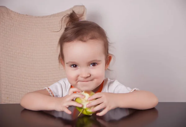 Adorable little girl eating an green apple — 图库照片