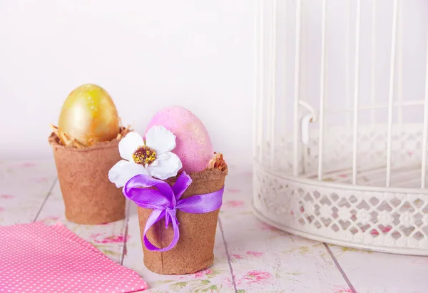 Oeufs roses et dorés de Pâques dans des pots sur la table — Photo