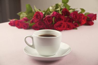 Bir fincan kahve ve masanın üzerine gül