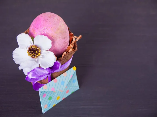 Œuf rose de Pâques dans un pot avec enveloppe sur le fond noir — Photo