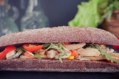 Hindi göğsü, peynir, marul, roka, domates ve soğan siyah plaka ile baget sandviç.