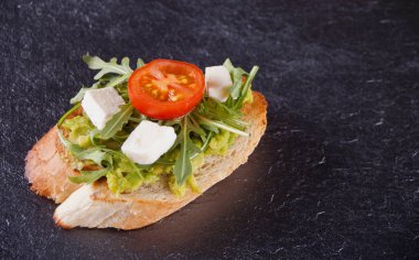 Domates, beyaz peynir ve roka siyah plaka ile tost ekmek dilimlenmiş