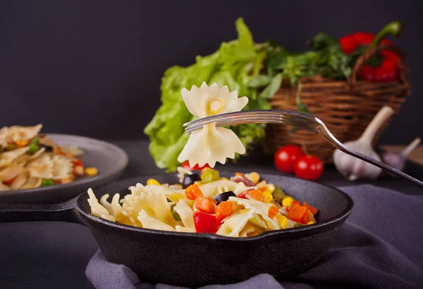 Ιταλικά ζυμαρικά φιογκάκια με mix λαχανικά σε ένα τηγάνι σιδήρου μαύρο — Φωτογραφία Αρχείου