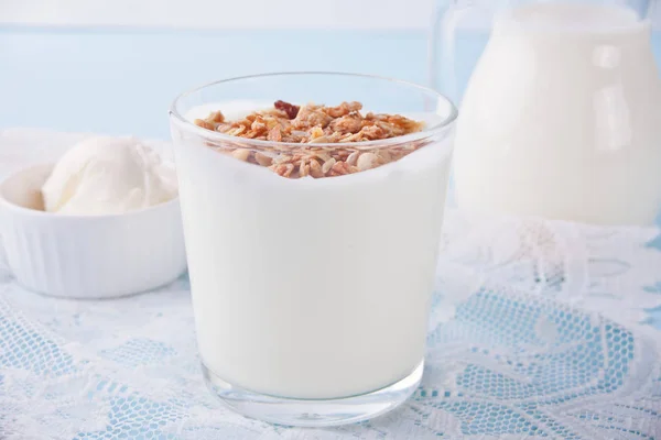 Гранола с йогуртом в стакане, молоком и сливочным сыром на синем столе — стоковое фото