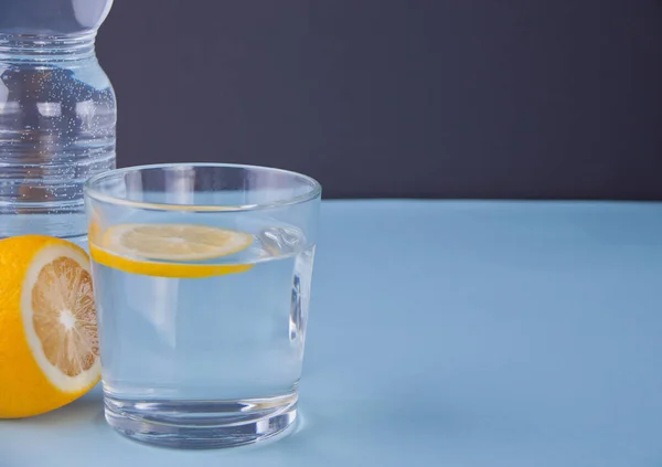 Agua con limón sobre el fondo azul . — Foto de Stock