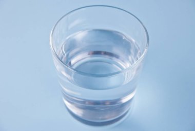 Mavi zemin üzerinde su olan bardak.